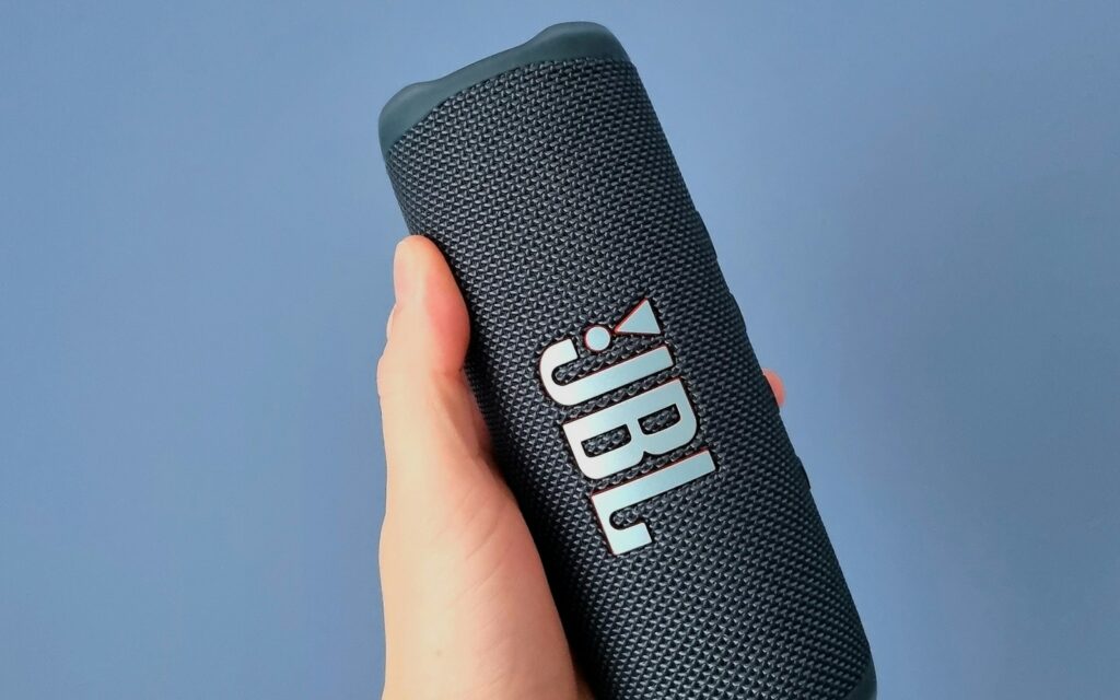 Portable Bluetooth speaker held against a blue background